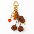 Cherry Charm Keychain with gold heart clasp, mini teddy bear, textured chocolate bar, heart pendant, and braided leather cherries.
