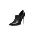 A black leather stiletto heel with a pointed toe and elastic upper detail, photographed on a white background.
