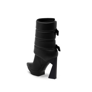 A black puffy vegan leather platform boot with adjustable straps and geometric high heel, photographed on a white background.